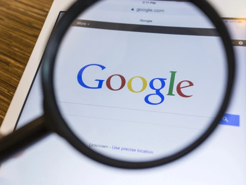 Une loupe grossit le mot Google sur une page de recherche